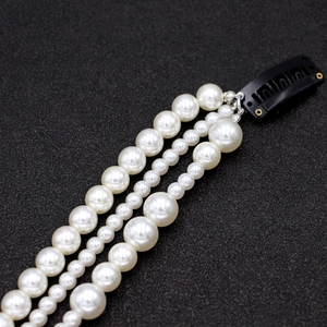 Barrette à trois rangs de perles blanches avec clip BB noir sur fond noir texturé