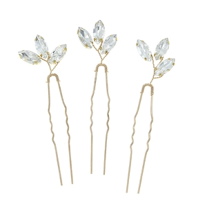 Macro detail of three gold U-shaped bridal hair pins with marquise crystal leaf designs