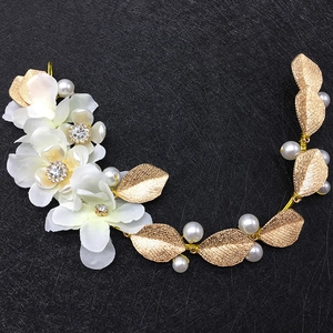 Détail du serre-tête de mariée avec fleurs en tissu blanc, feuilles dorées et perles