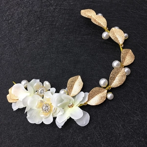 Détails d'une vigne de cheveux de mariée avec fleurs en tissu blanc et feuilles dorées