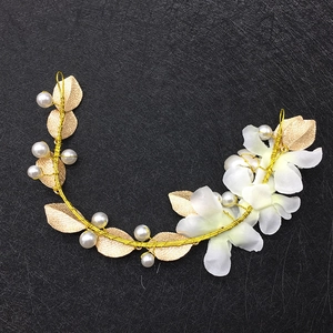 Gros plan détaillé de fleurs en tissu blanc et feuilles dorées sur bandeau de mariée