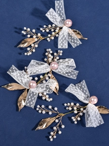 Detail of white lace bows and pink pearls on golden bridal hair accessories set