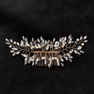 Close-up of rose gold bridal hair comb with crystals and pearls on leather background
