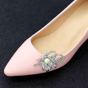 Close-up of sparkling rhinestone flower shoe clip with pearl on pink flat shoes