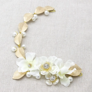 Détail du bandeau de mariée avec fleurs en tissu blanc, feuilles d'or et perles
