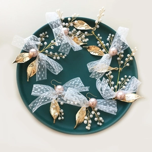 Close-up of bridal headpiece set with white lace bows and pink pearls in a green dish