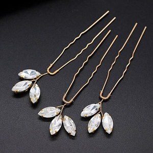 Set of three handcrafted gold U-shaped bridal hair pins with crystal leaf decorations