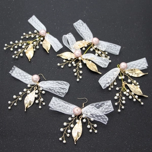 Detail of 5-piece bridal hair accessories with white lace bows and pink pearls on black texture