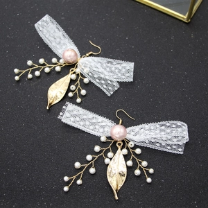 Elegant gold earrings with white lace bows, pink pearls, and delicate leaf pendants
