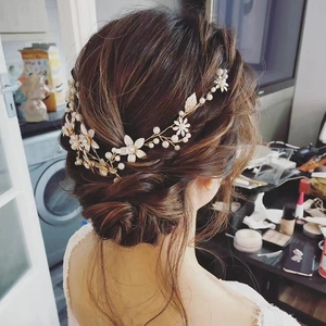 Bijou de cheveux doré pour mariée avec fleurs blanches et perles sur une coiffure relevée