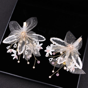 Detailed macro view of two handmade gold lace butterfly hair clips with pearls and beads