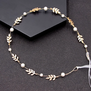 Serre-tête de mariée doré avec feuilles et perles sur un fond texturé sombre élégant