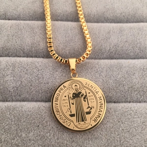 Detailed macro view of gold St. Benedict medal pendant on classic box chain necklace
