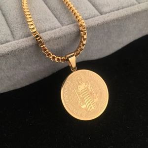 Detailed close-up of a gold Saint Benedict coin pendant on a square box chain necklace