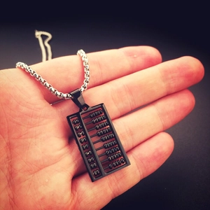 Macro detail of a black matte abacus pendant necklace held in hand with silver chain