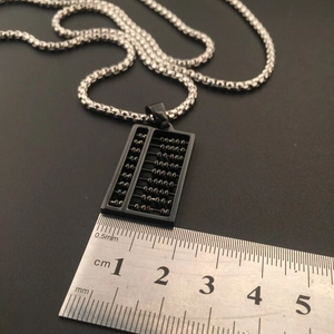 Detailed close-up of a hip-hop abacus pendant necklace next to a measuring ruler