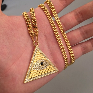 Détail macro de la chaîne cubaine dorée et du pendentif triangle avec l'œil de providence