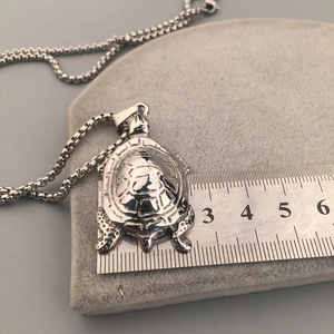 Détail macro du pendentif tortue argenté avec texture de carapace et règle en acier