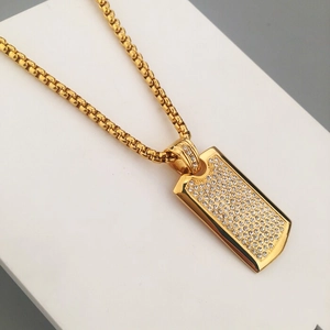 Close-up of hip hop gold dog tag pendant with sparkling pavé crystals and square link chain