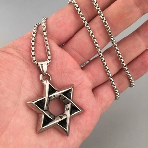 Detail of a large silver hexagram star pendant with box chain held by hand for size