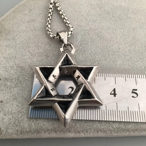 Macro shot of a vintage silver star pendant with religious symbols next to a ruler