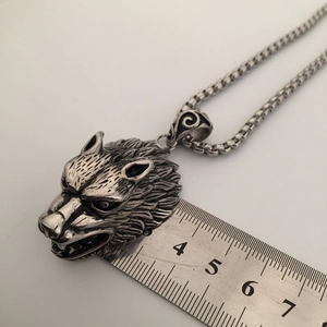 Detailed size measurement of the vintage wolf head pendant using a metal ruler