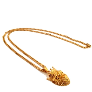 Detail of gold lion head pendant with crown and Greek key pattern on cuban chain