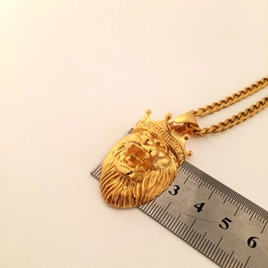 Detail shot of golden lion head crown pendant showing dimensions with a metal ruler