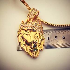 Close-up of golden hip hop lion head pendant with crown and size reference ruler