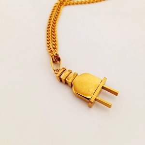 Detalle de un colgante creativo con forma de enchufe chapado en oro sobre cadena de eslabones