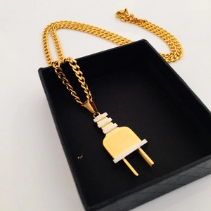 Detalle de un colgante de enchufe hip-hop dorado sobre una caja de regalo negra