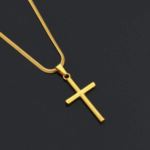 Macro shot of minimalist gold plated stainless steel cross pendant on sleek snake chain