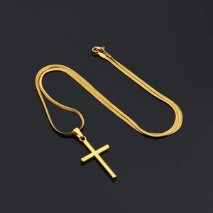 Macro shot of minimalist gold plated cross pendant with a flat snake chain on a black surface