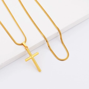 Polished gold cylinder cross pendant with sleek snake chain on white display
