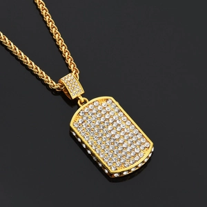 Gros plan du pendentif rectangulaire plaqué or serti de cristaux sur chaîne torsadée