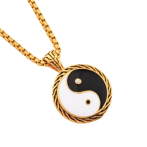 Macro shot of titanium steel Tai Chi pendant with Yin Yang motif and gold box chain