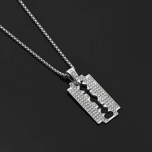 Détail macro du pendentif lame de rasoir hip hop argenté avec strass blancs étincelants