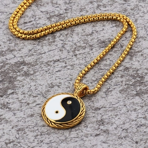 Close-up of gold Yin Yang pendant with rope border and crystals on a box chain