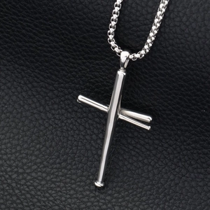 Detailed view of polished stainless steel baseball bat cross pendant on leather background