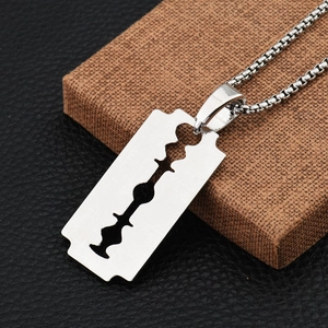 Détail macro d'un pendentif lame de rasoir argenté sur chaîne box au style punk chic