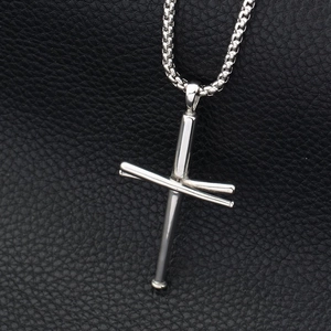 Close-up of silver baseball bat cross pendant with box chain on black leather background