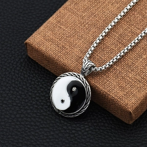 Macro shot of Tai Chi Yin Yang pendant with silver textured frame on a black leather base