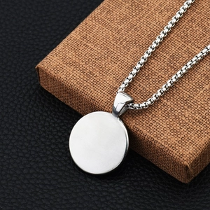 Detailed close-up of a silver Tai Chi pendant and box chain on a brown jewelry box