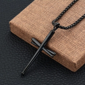 Close-up of hip hop cross pendant made of three black baseball bats on box chain