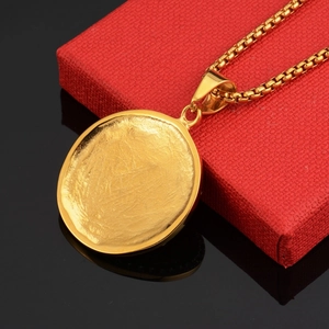 Detailed macro view of a large gold oval pendant with textured finish and box chain
