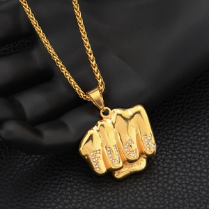 Collier avec pendentif poing doré orné de zircons sur un support de présentation noir