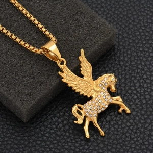 Golden Pegasus pendant necklace with sparkling crystals and a box chain on a stone surface