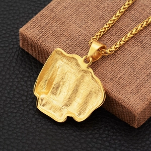 Détail du pendentif poing doré avec dos texturé et chaîne épi sur un coffret à bijoux