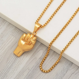 Polished gold fist pendant necklace with durable box chain on a geometric display stand