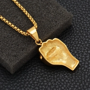 Detail of gold box chain and textured hollow back of the metal fist pendant